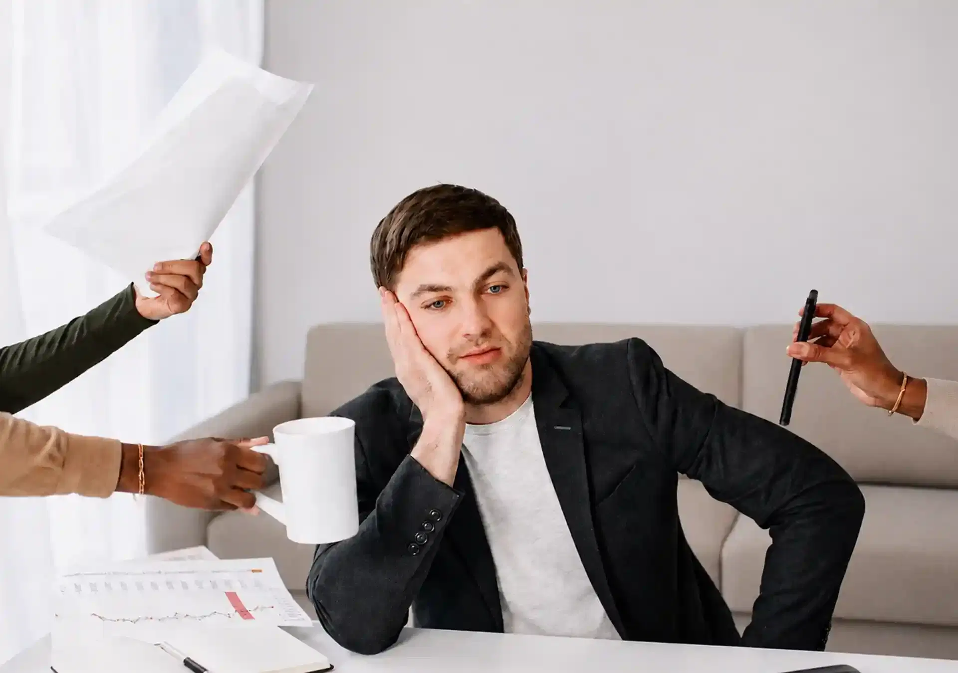 Image of a man at a desk feeling overwhelmed by the demands of his job and coworkers