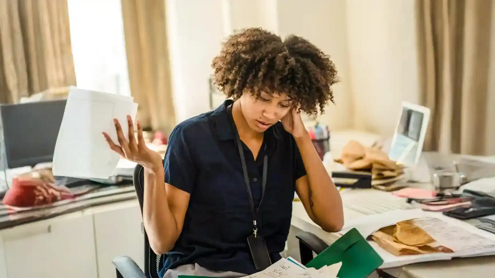 Image of a woman at her desk feeling overwhelmed by her work